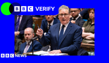 Prime Minister Sir Keir Starmer standing at the House of Commons dispatch box in a dark suit holding a pen in his right hand