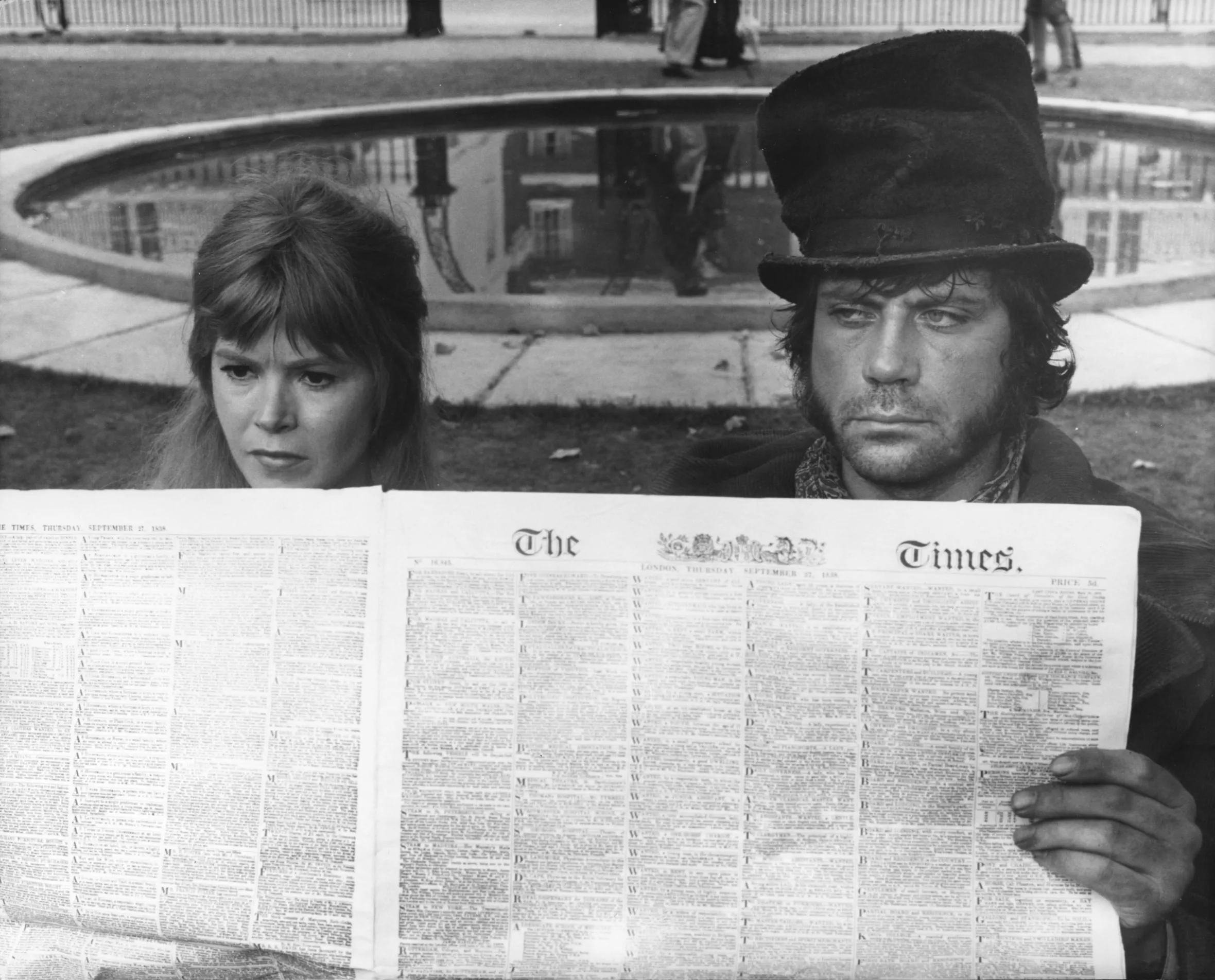 Shani Wallis as Nancy and Oliver Reed as Bill Sikes look out from behind a newspaper.