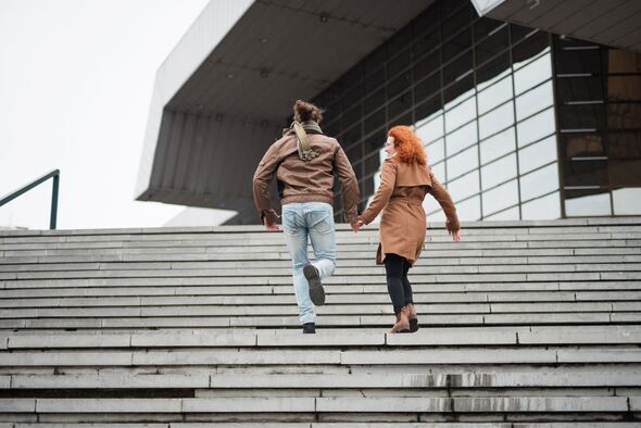 Back view of a couple running up the stairs. Back view of a couple running up the stairs.
