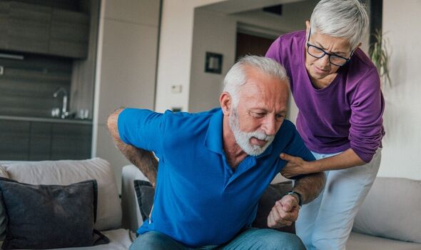 An elderly couple help one another