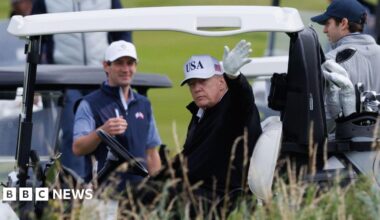 Donald Trump waves to onlookers from his golf buggy