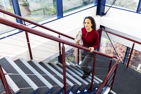 Businesswoman moving up on staircase at office Businesswoman moving up on staircase at office