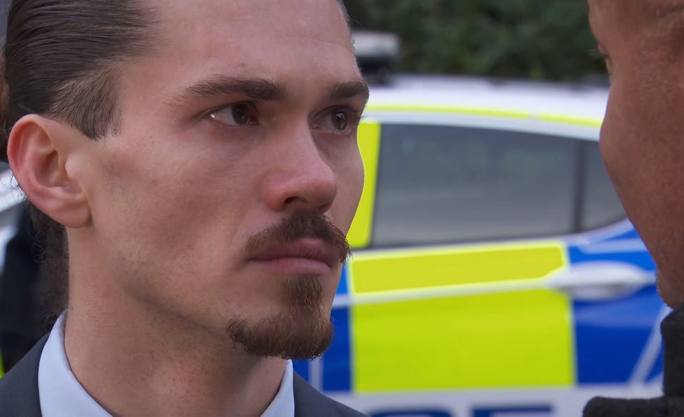 hollyoaks sully getting tearful stood in front of a police car wearing a suit and talking to donny