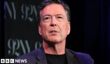 Former FBI director James Comey wearing a dark suit, with a dark background