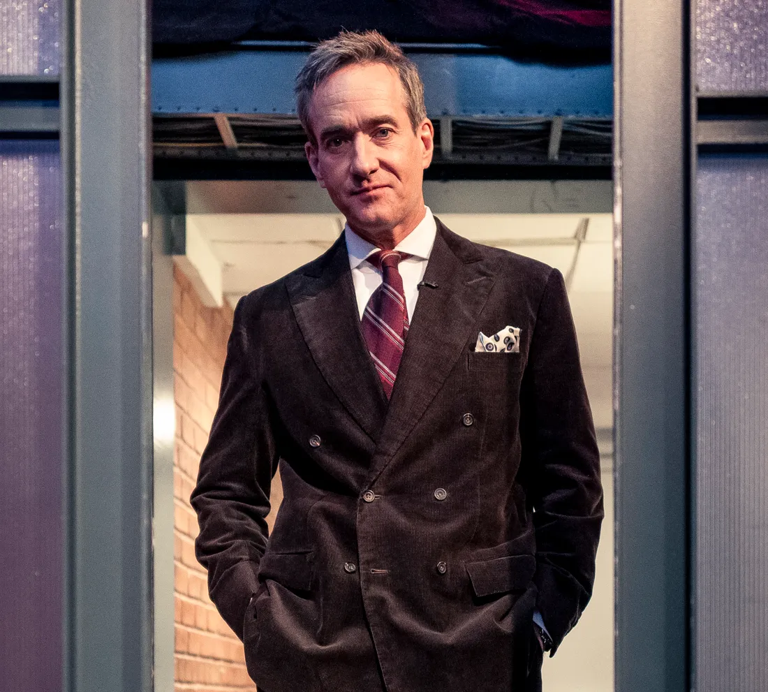 Actor Matthew Macfadyen stands in a doorway wearing a brown corduroy suit.