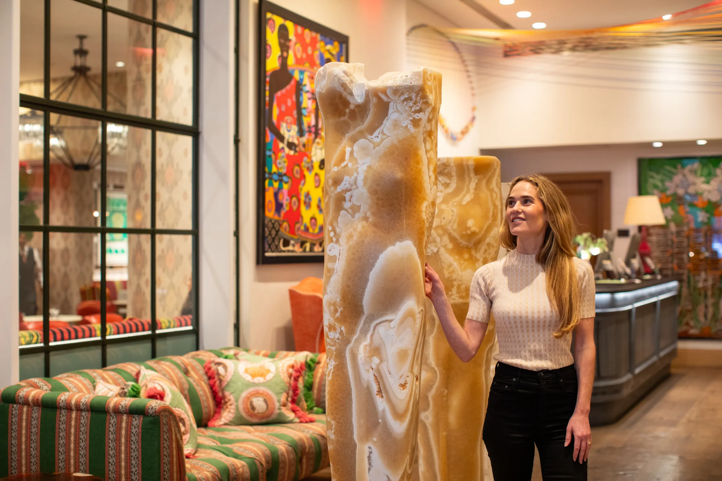 Willow Kemp touching a light brown and white abstract sculpture.