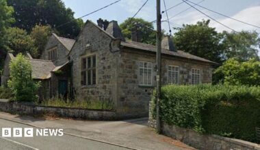 The outside of a luxurious stone house with a utility pole on the pavement out front.