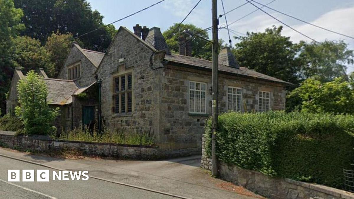 The outside of a luxurious stone house with a utility pole on the pavement out front.