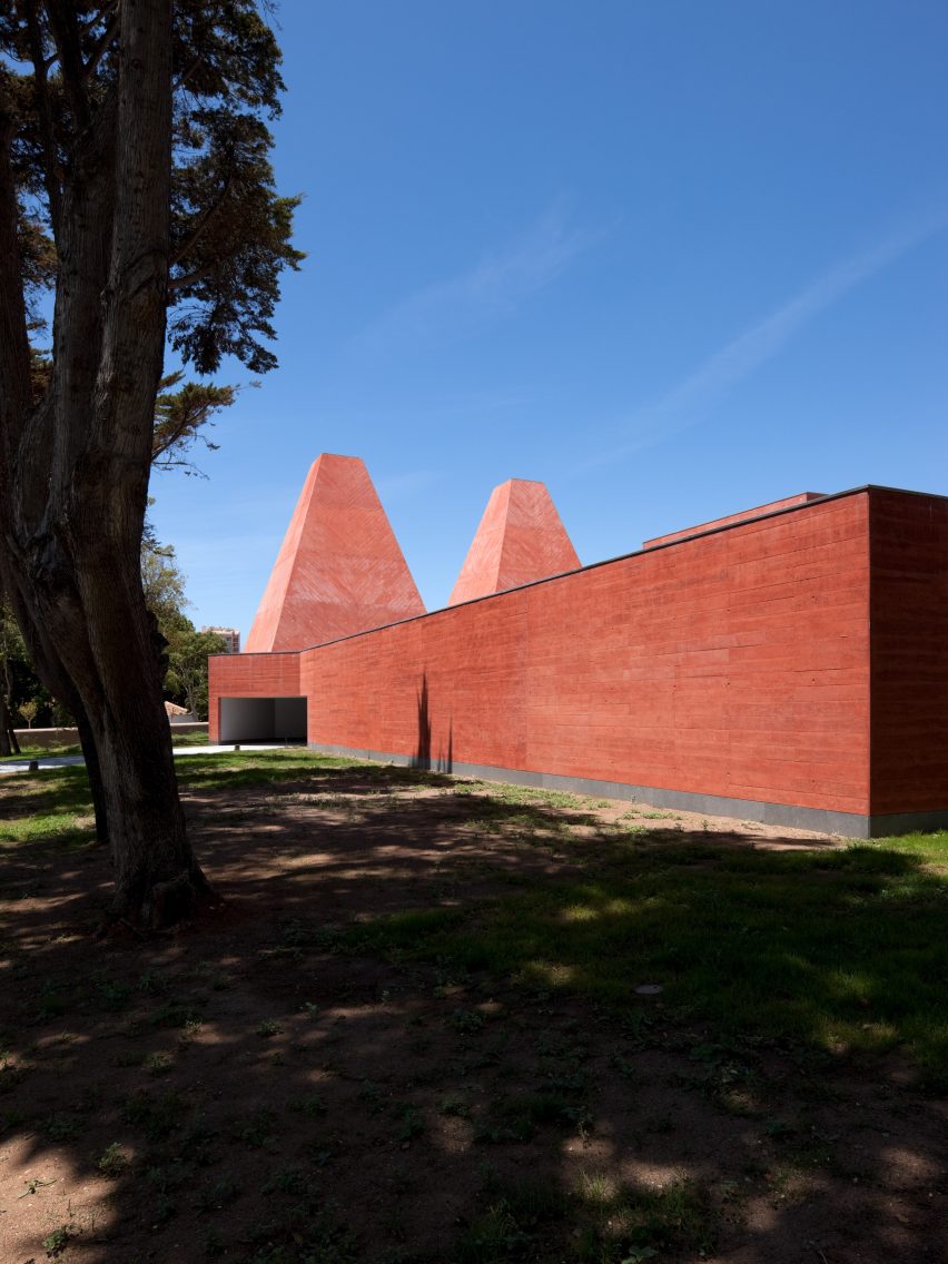 Casa das Histórias museum in Cascais with red concrete walls and two pyramidal towers rising above surrounding trees