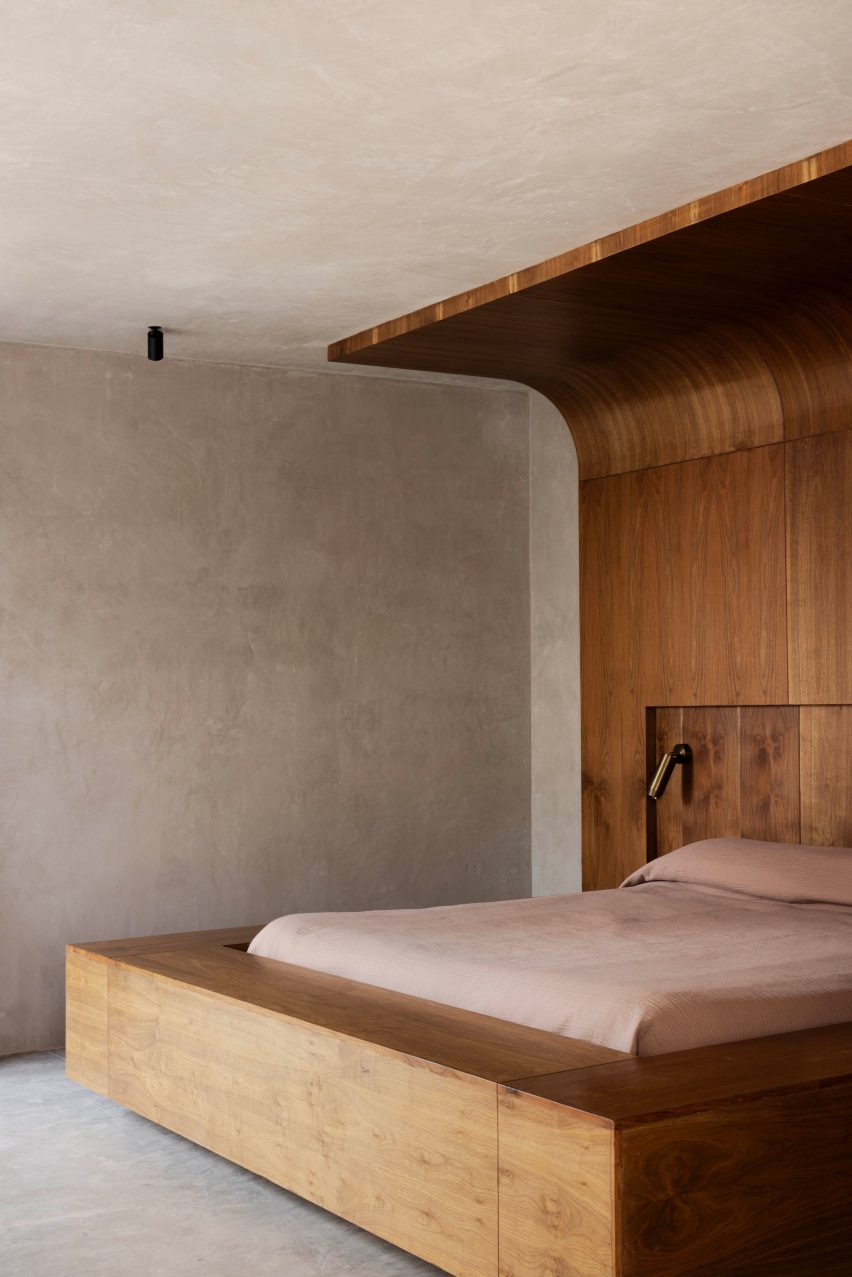An exaggerated wooden bed frame including a giant headboard that swoops onto the ceiling