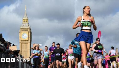 A large group of people participate in the London Landmarks Half Marathon, running on a city street with the Elizabeth Tower visible in the background under a cloudy sky.