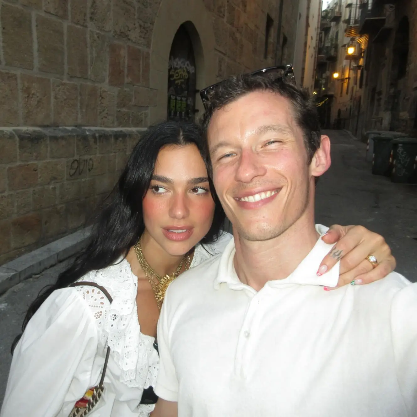 Dua Lipa and a man posing for a selfie in an alleyway.