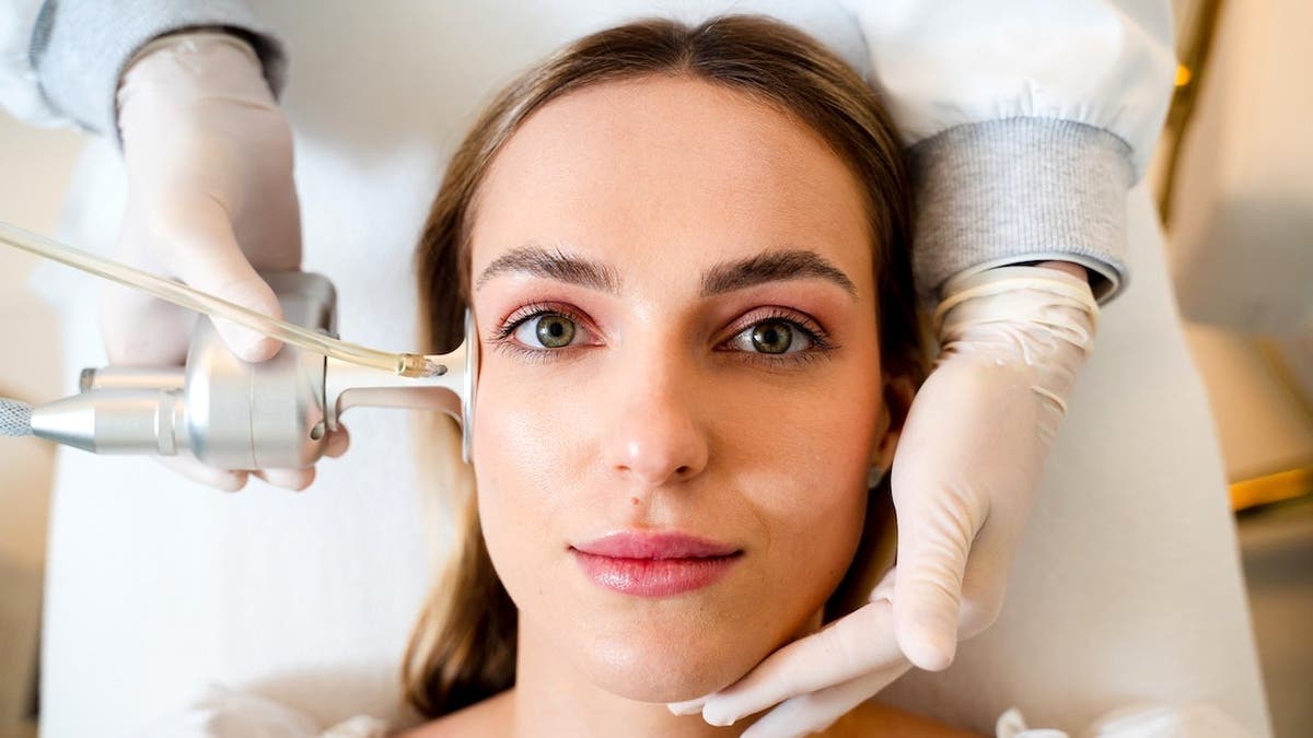 A woman receiving CO2 laser treatment on her facial skin to reduce wrinkles and scars.