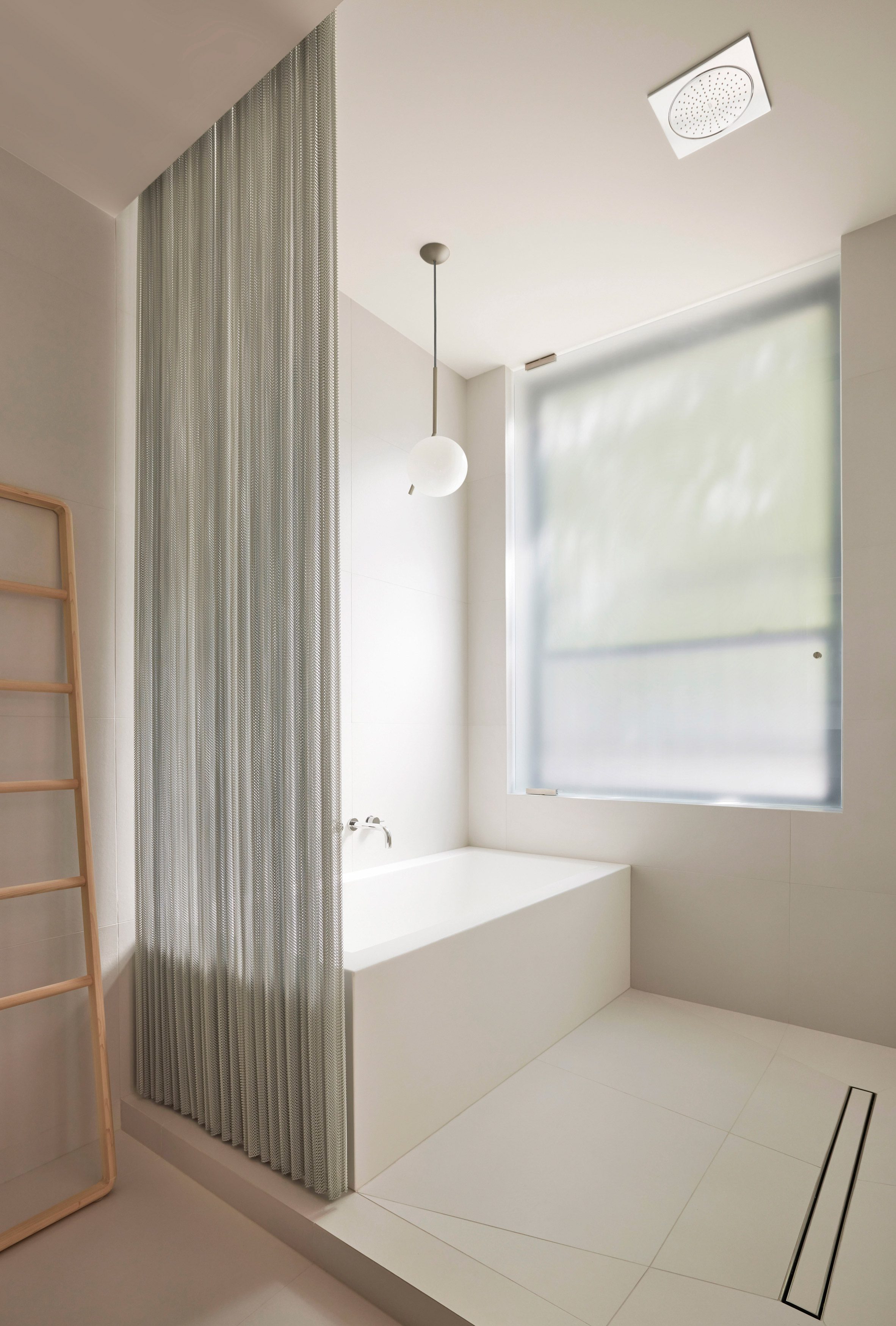 In a beige-tiled primary bathroom, a chainmail curtain demarcates the wet area