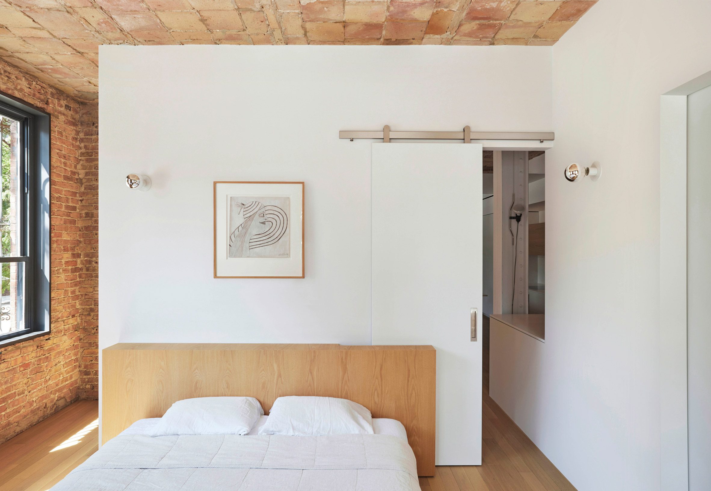 White walls contrast clay, brick and oak in a primary bedroom
