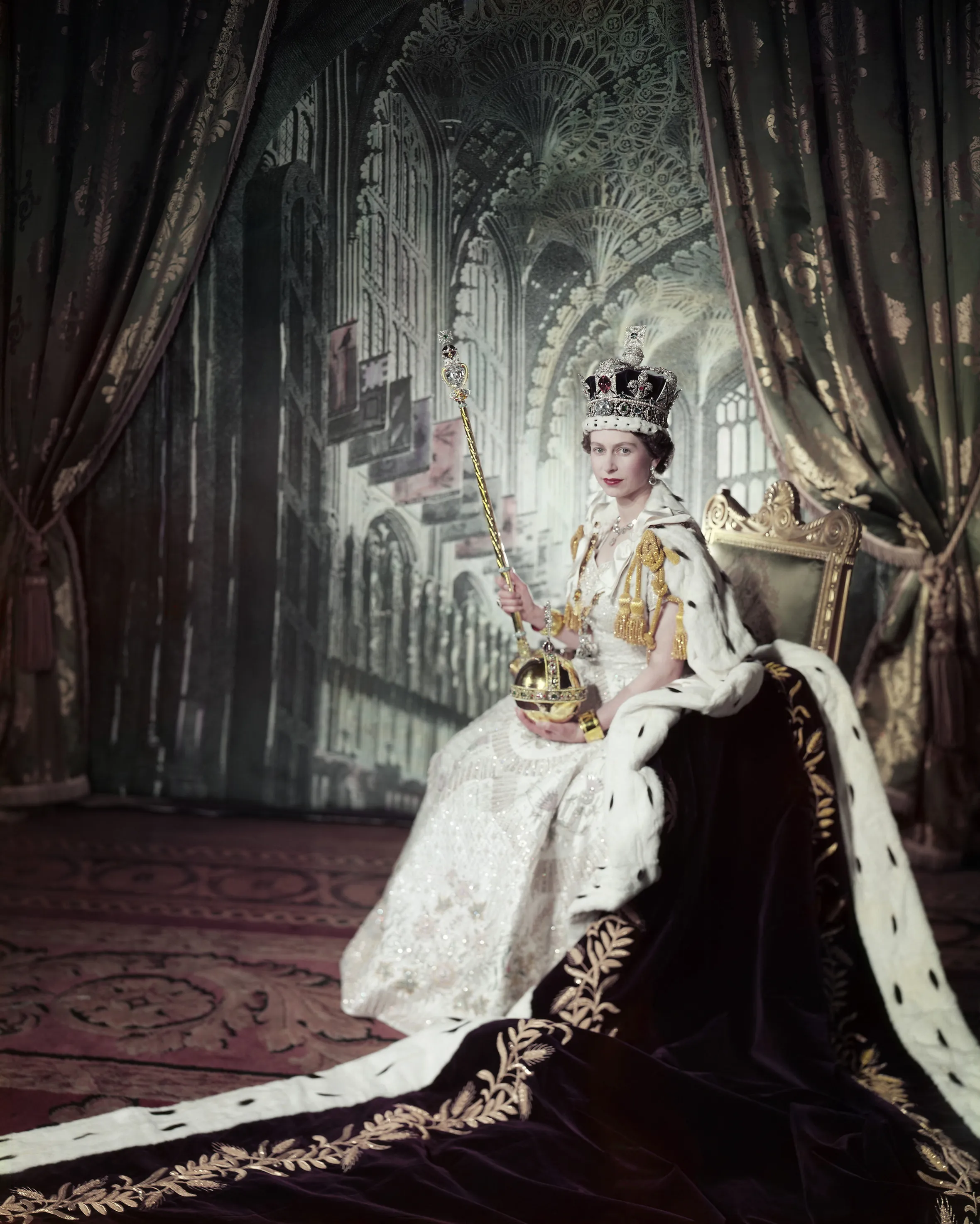 Queen Elizabeth II on her Coronation Day in 1953, wearing a crown and royal robes and holding a scepter and orb.