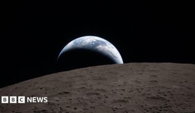 Image of Earthrise poking out over the surface of the moon