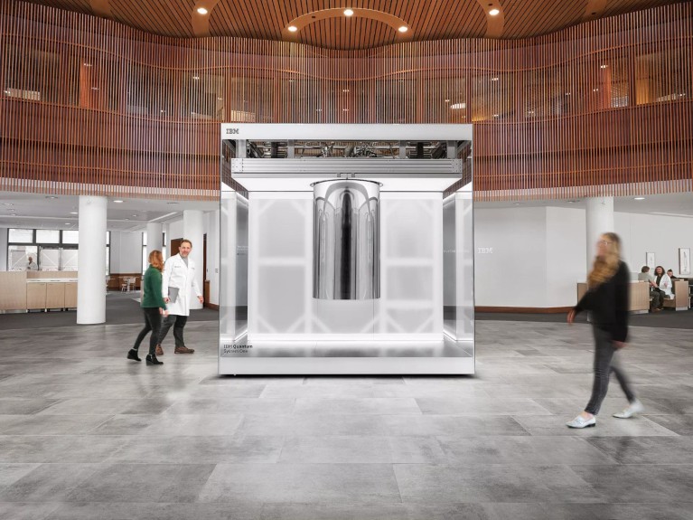 The IBM Quantum System One computer, housed in a clear glass cube in the atrium at the Cleveland Clinic, as people walk by.