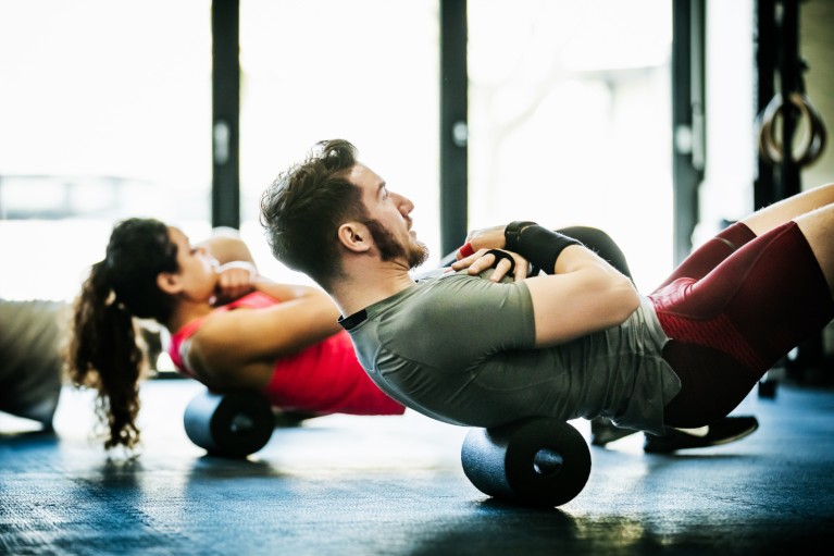 A man and woman performing floor exercises together in a gym.