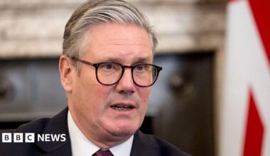 A close up of Prime Minister Sir Keir Starmer in Downing St, with a blurred background and the UK flag behind him.