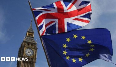 A Union Jack and European Union flag fly against a blue sky in front of Big Ben in central London.