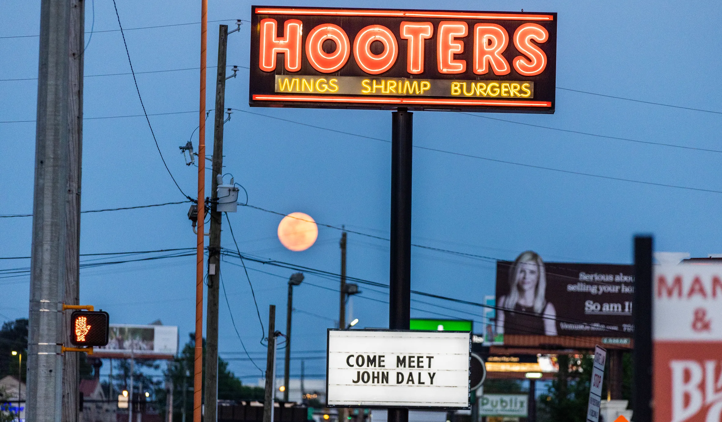 A Hooters restaurant sign advertises an appearance by John Daly.