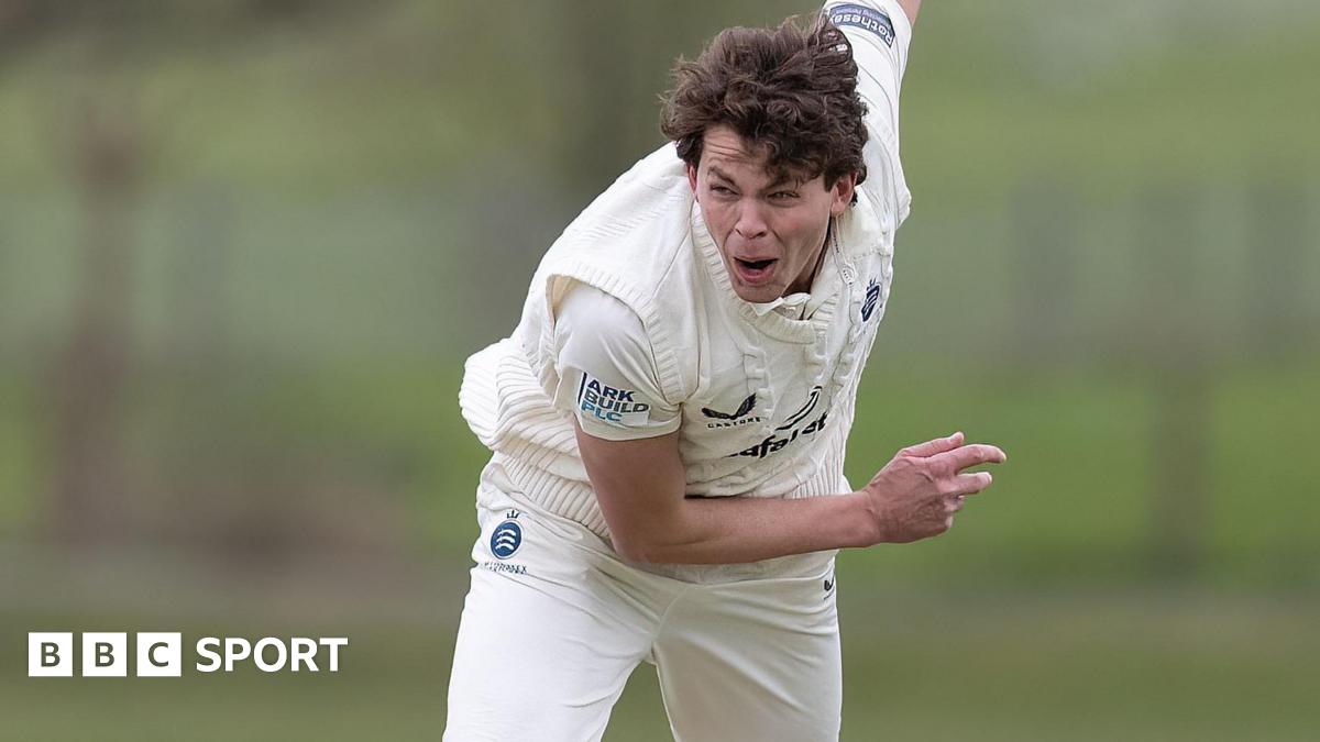Henry Brookes crouched forward with his right arm held up in the air behind him after he bowls a ball during a friendly for Middlesex