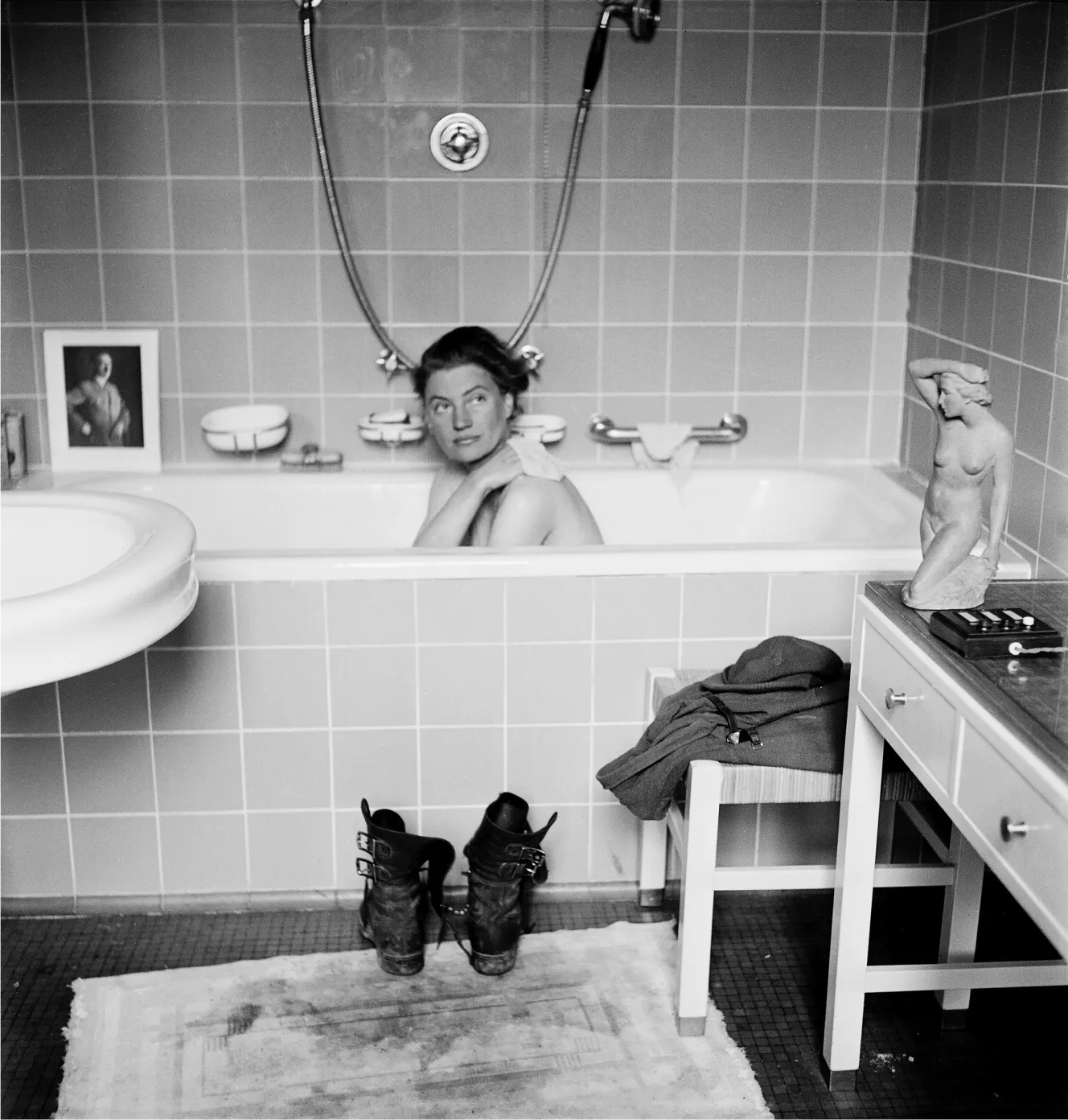 Lee Miller bathing in Hitler's bathtub, with a framed picture of Hitler on the tub's edge.