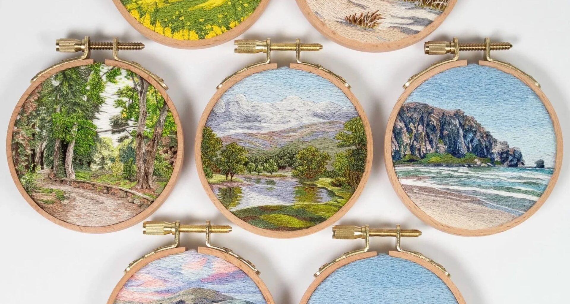 a collection of lush landscape embroideries in light wood hoops by Cassandra Dias
