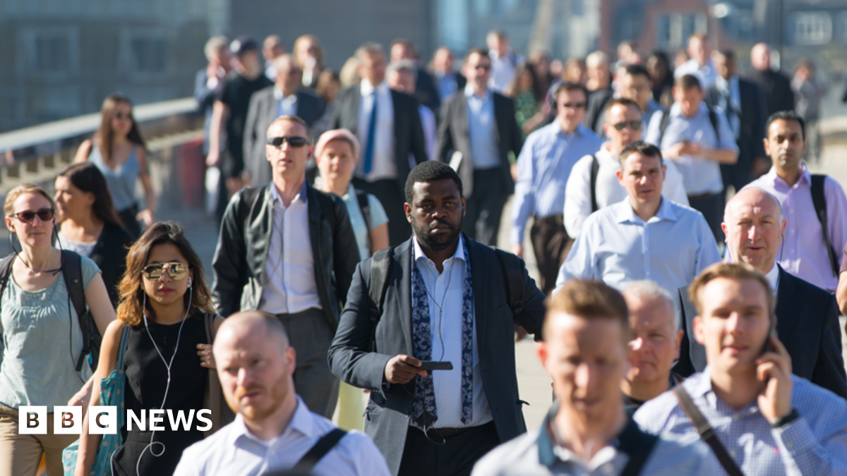 men and women mostly smartly dressed in shirts and jackets walking towards the camera seemingly in London over a bridge in the sunshine