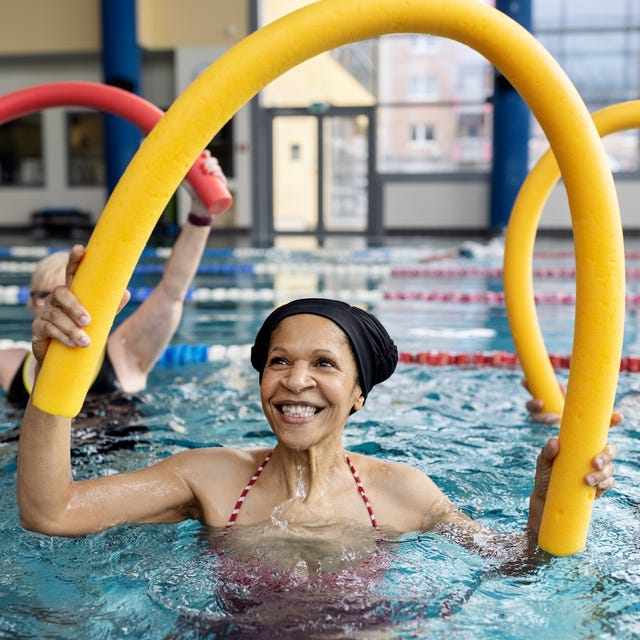 Healthy senior woman doing swim noodle exercises in aerobics pool class Healthy senior woman doing swim noodle exercises in aerobics pool class