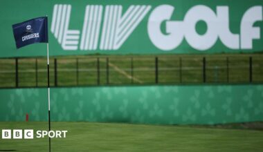 A flag on a golf course green in front of a sign that says 'LIV Golf'