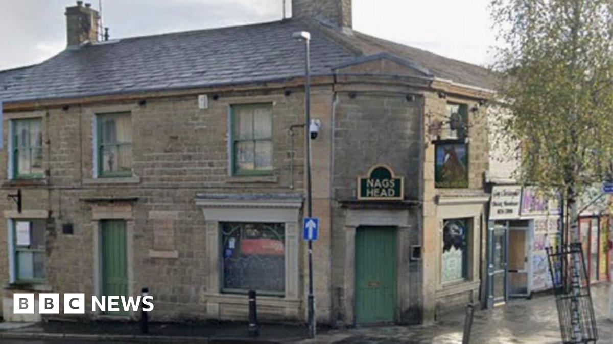 Street view image of the Nag's Head pub. A stone building on a street corner with green windows and doors and a sign in black with gold wording over the door, which is on the corner, that says NAG'S HEAD