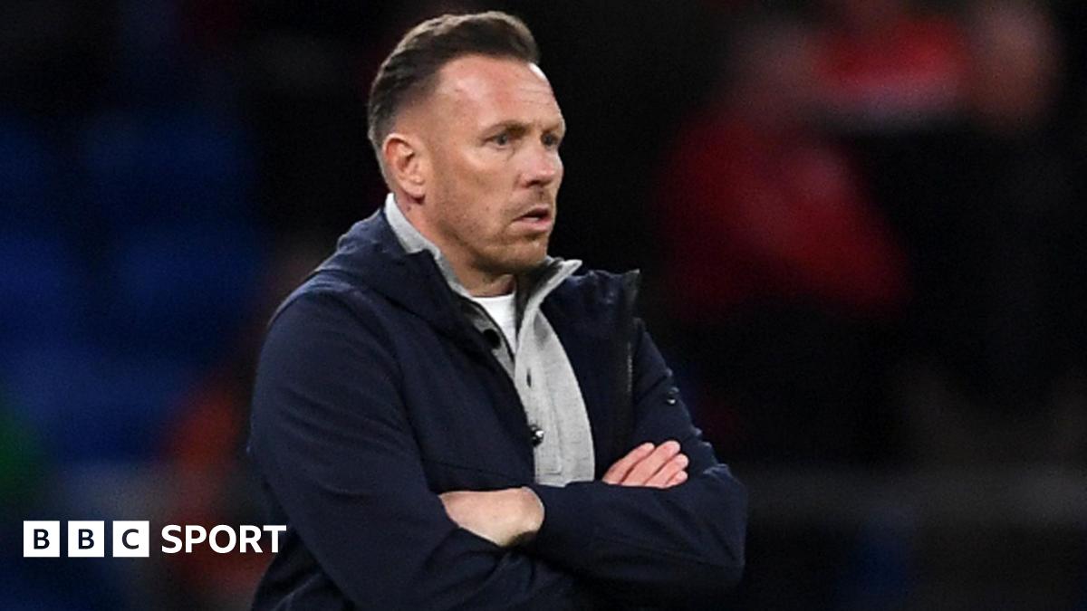 Craig Bellamy, in an open dark jacket with a grey top underneath, looks on with a focused stare during Wales' match against Northern Ireland