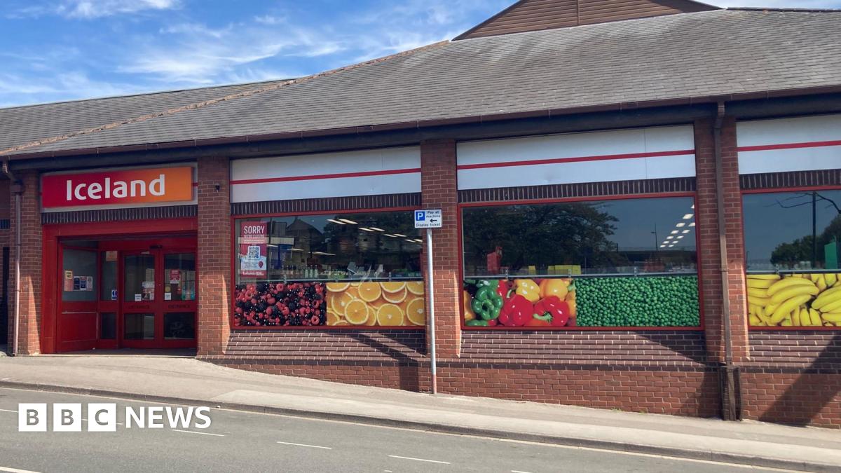 A shopfront with pictures of fruit in the window and an orange and red signage which reads "Iceland"