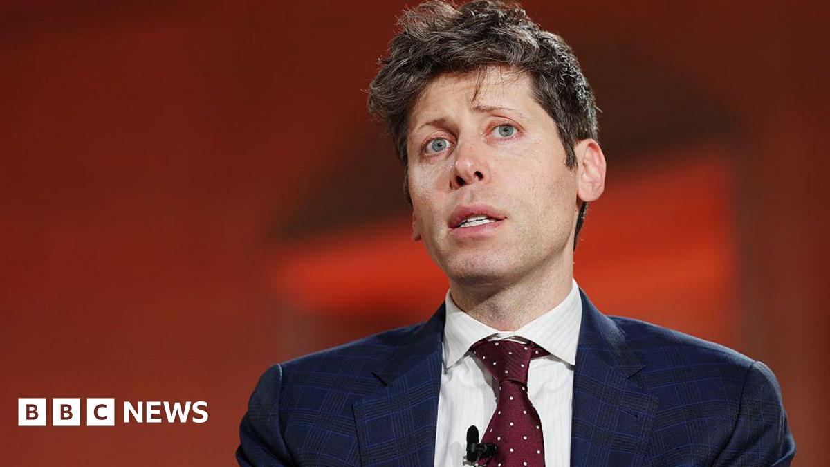 Sam Altman against red background, wearing blue suit and red tie with white dots, looks up and to the side