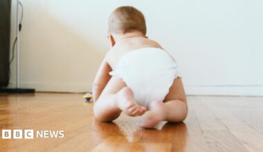 A baby crawling on a wooden floor