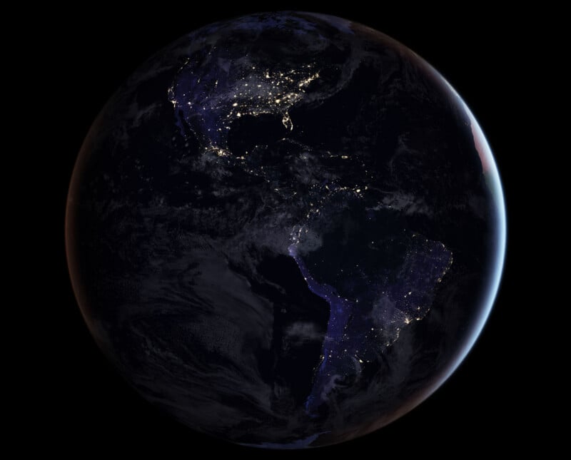 A view of Earth from space at night, showing North and South America with city lights illuminating populated areas, especially in the United States and parts of South America. The rest of the planet is mostly dark.