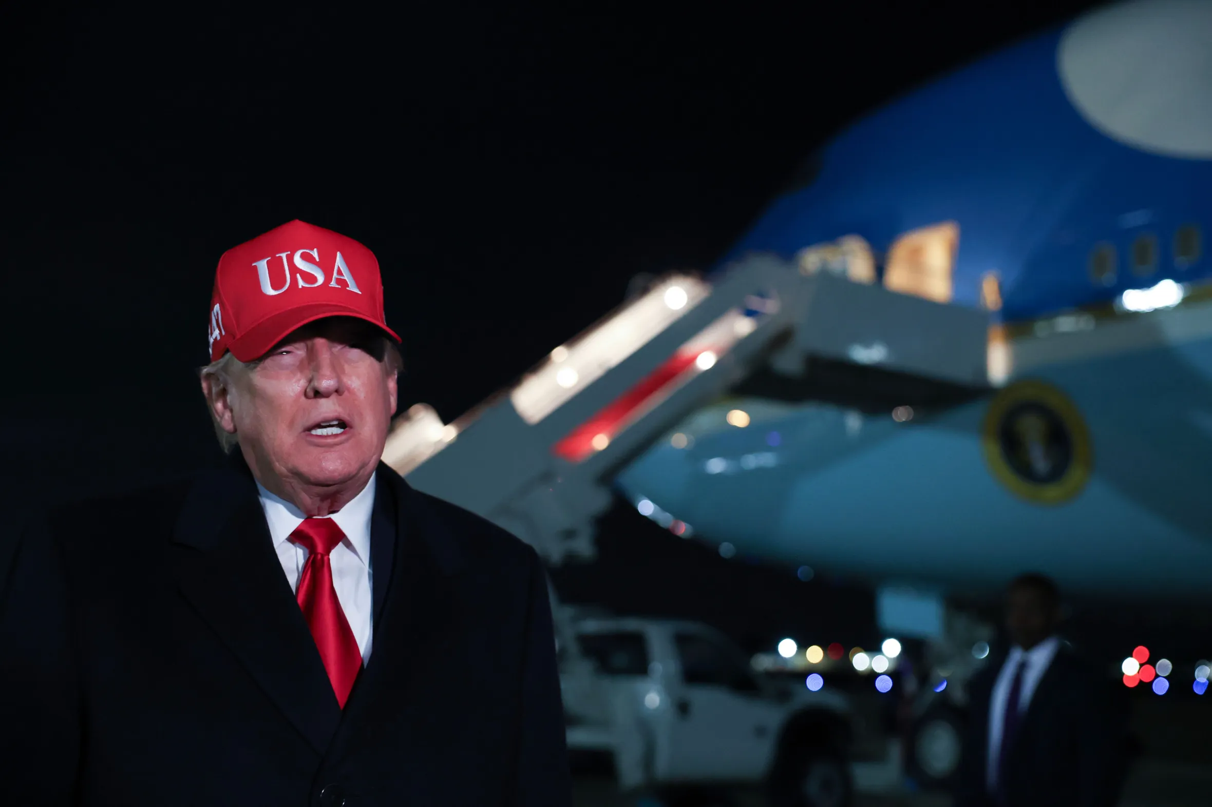 President Trump speaks to the media after disembarking Air Force One at night.