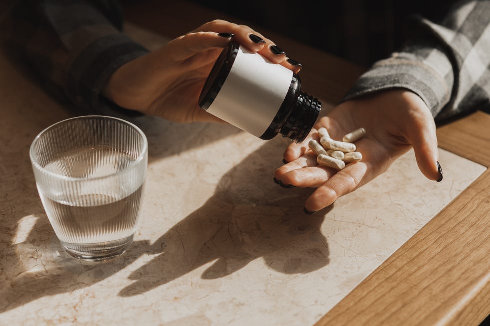 woman holding vitamin supplements in kitchen