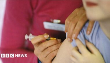 A close-up image of a person about to have a needle placed into their arm.