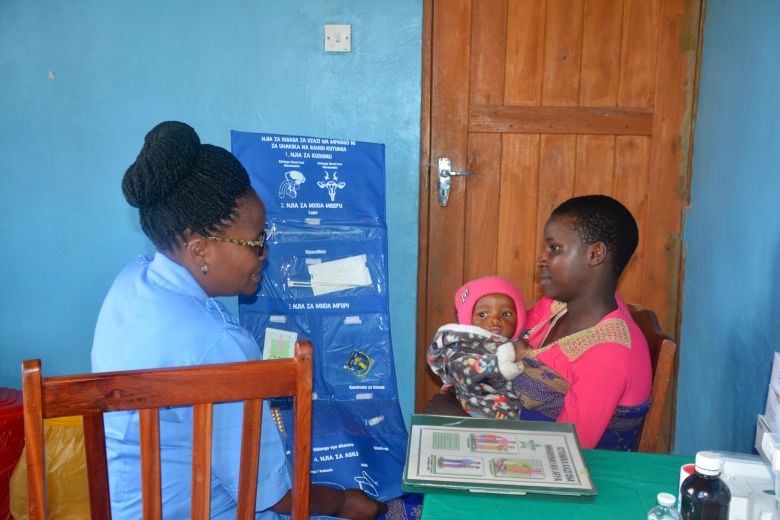 A clinical staff member explains different birth control options to a mother in Tanzania.