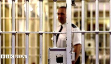 A prison officer walks down a wing of a prison.
