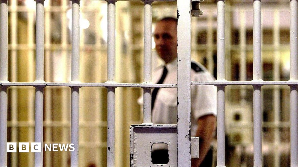 A prison officer walks down a wing of a prison.