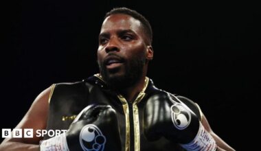 Lawrence Okolie in black boxing gloves and sleeveless black and gold zip-up top