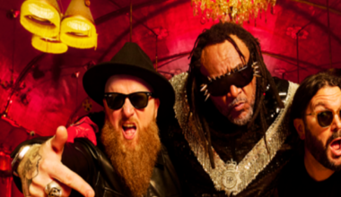 Benji Webbe on a pink bike. The other members of Skindred are behind him