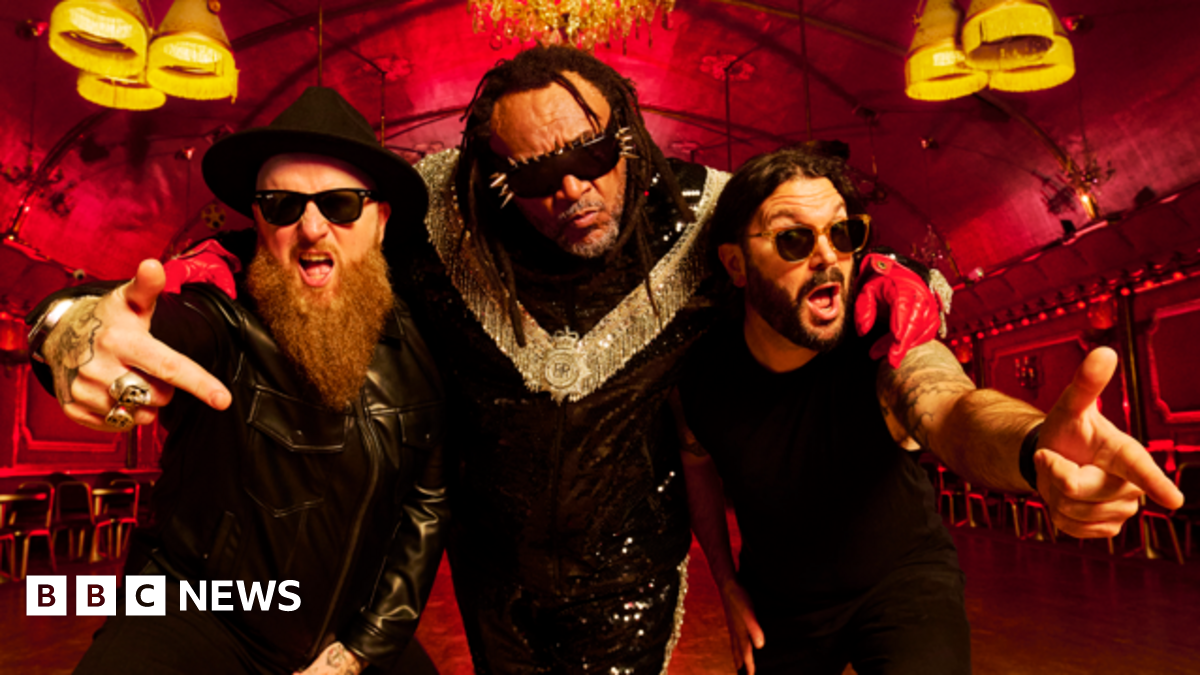 Benji Webbe on a pink bike. The other members of Skindred are behind him