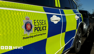 A close-up image of the side of an Essex Police car. The side of the door has the Essex Police logo on it