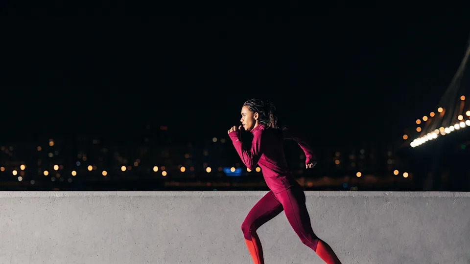 Young woman jogging in a city at night in the dark