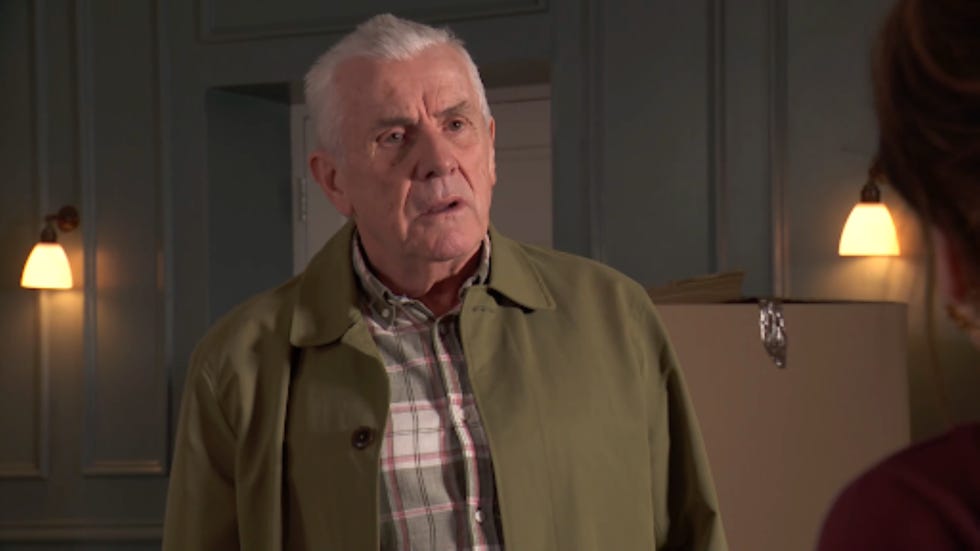 man in a green coat standing in a room